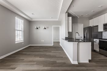 an open kitchen and living room with a large window and a black and white at Alexandria of Carmel Apartments, Carmel, IN